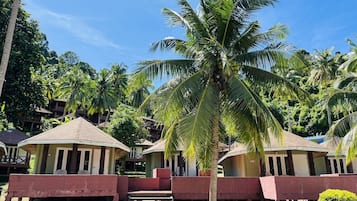 A resort with multiple bungalow-style buildings, palm trees, and a clear blue sky.