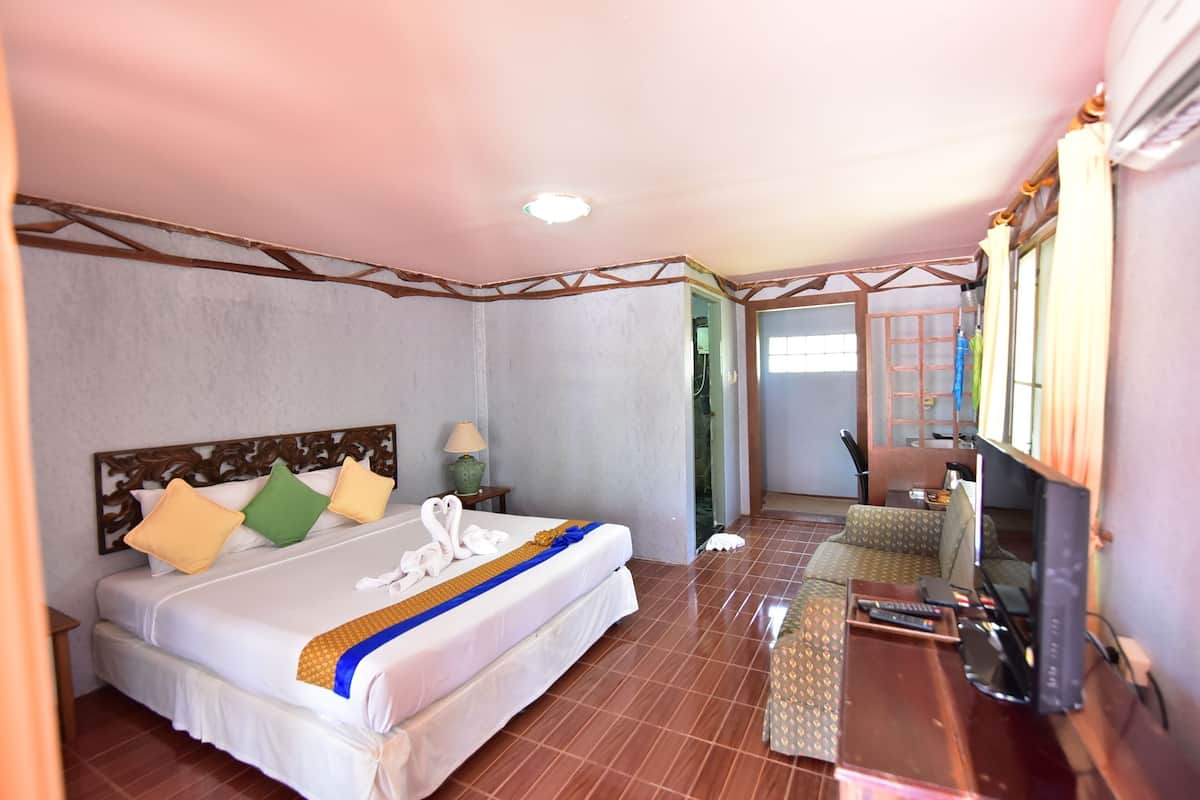 A hotel room with a bed, a TV, a sofa, and a bathroom visible through an open door.