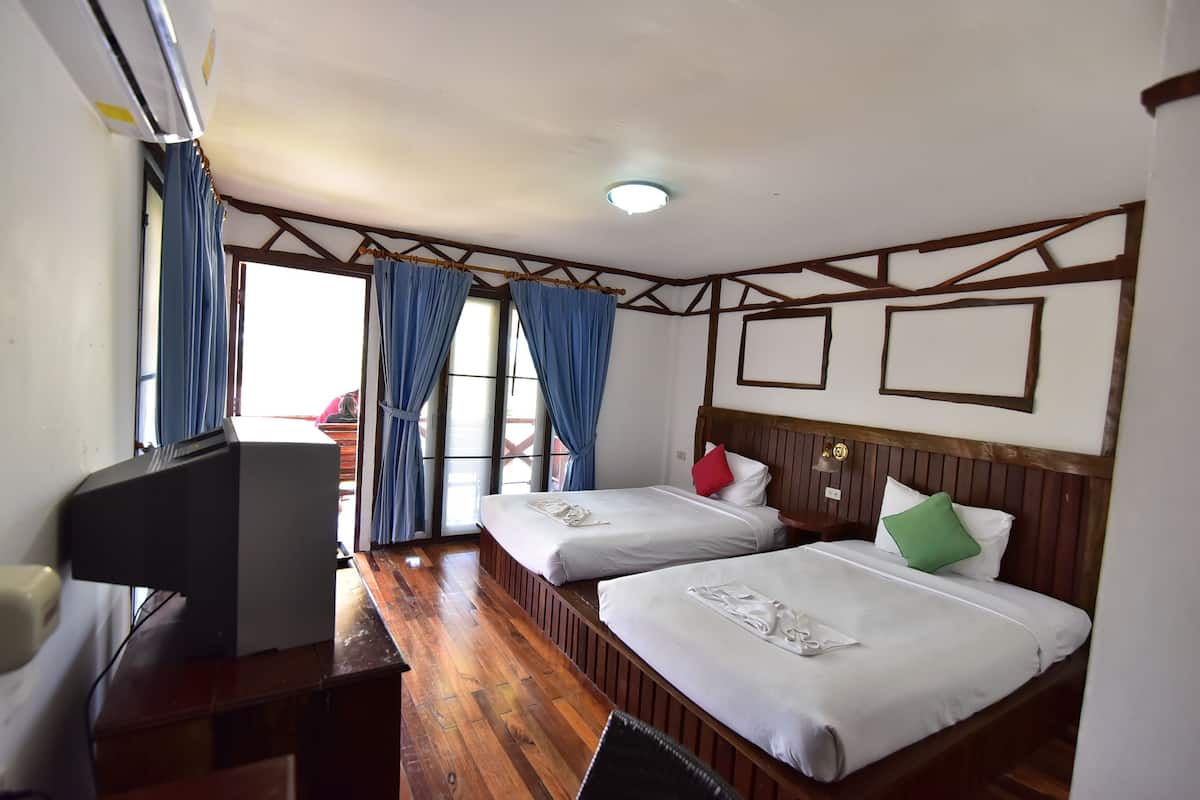 A hotel room with two beds, a desk with a computer, and a window with curtains.