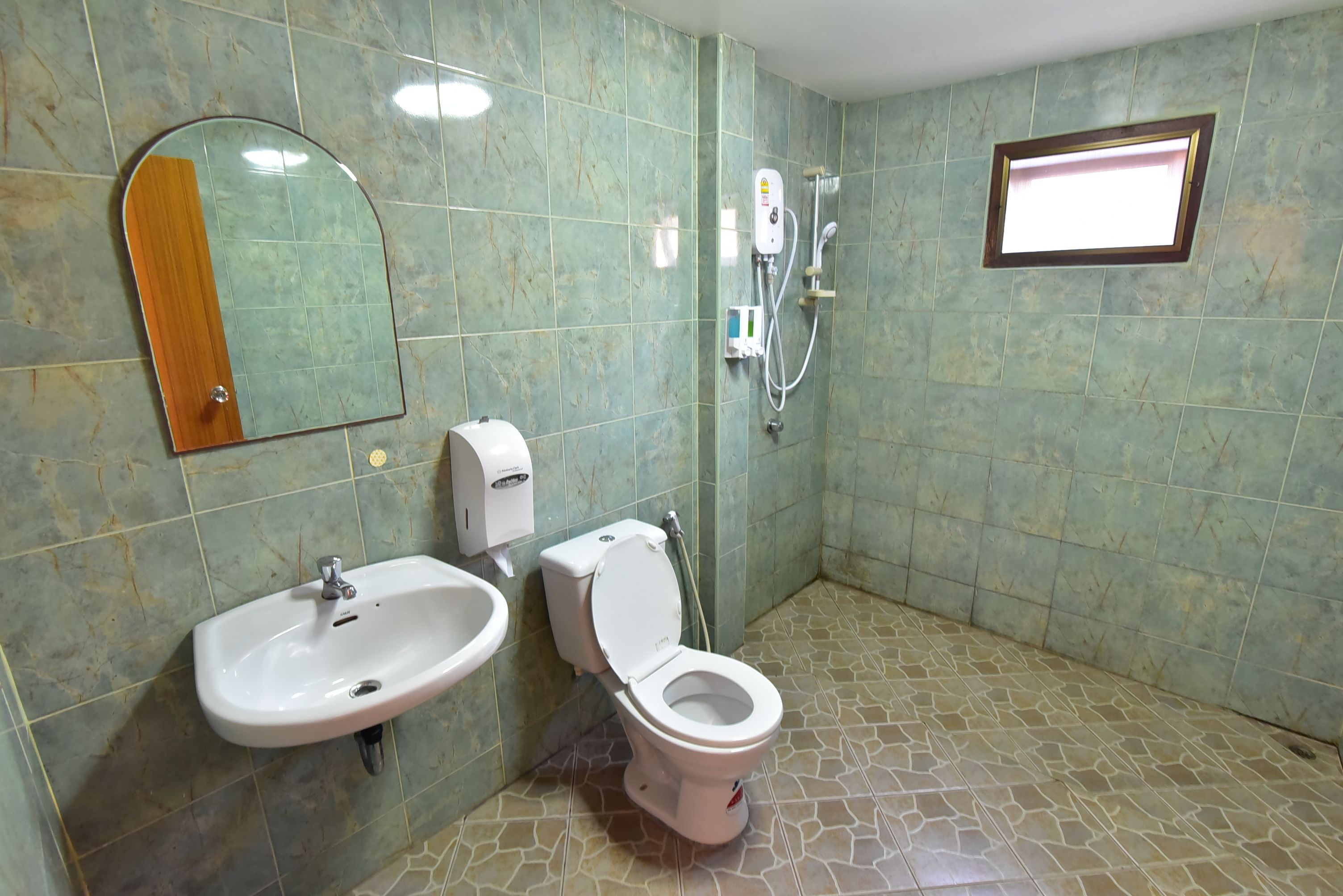 Un baño con lavamanos, inodoro, espejo y ducha.