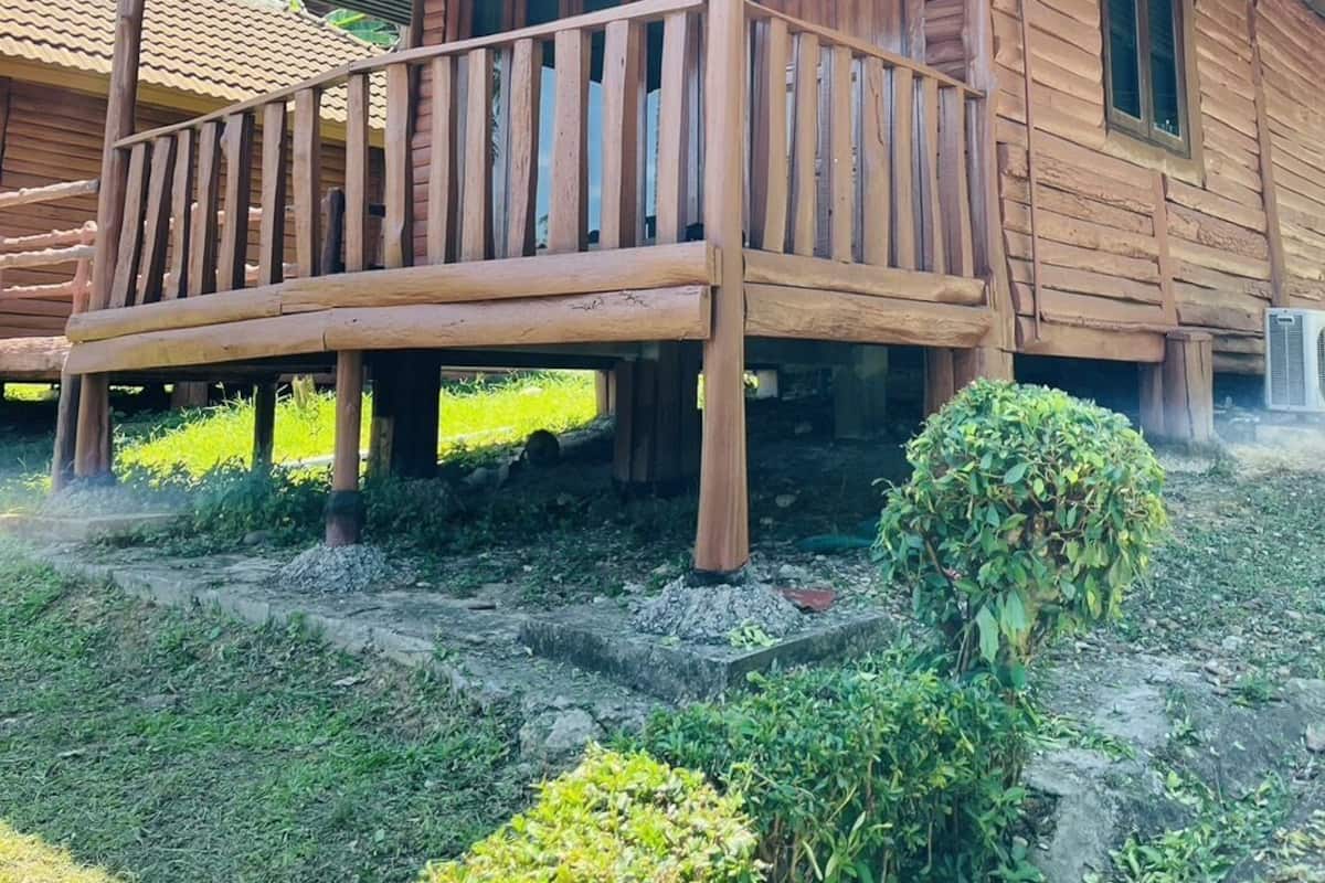 A wooden cabin with a porch, surrounded by greenery.