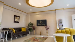 A modern living room with a dark sofa, yellow cushions, a round ceiling light, and a 'Bilge Hotel' sign on the wall. - Bilge Suite Hotel (Corum)