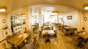 A spacious dining area with multiple tables and chairs, wooden flooring, and a modern ceiling design. - Bilge Suite Hotel (Corum)