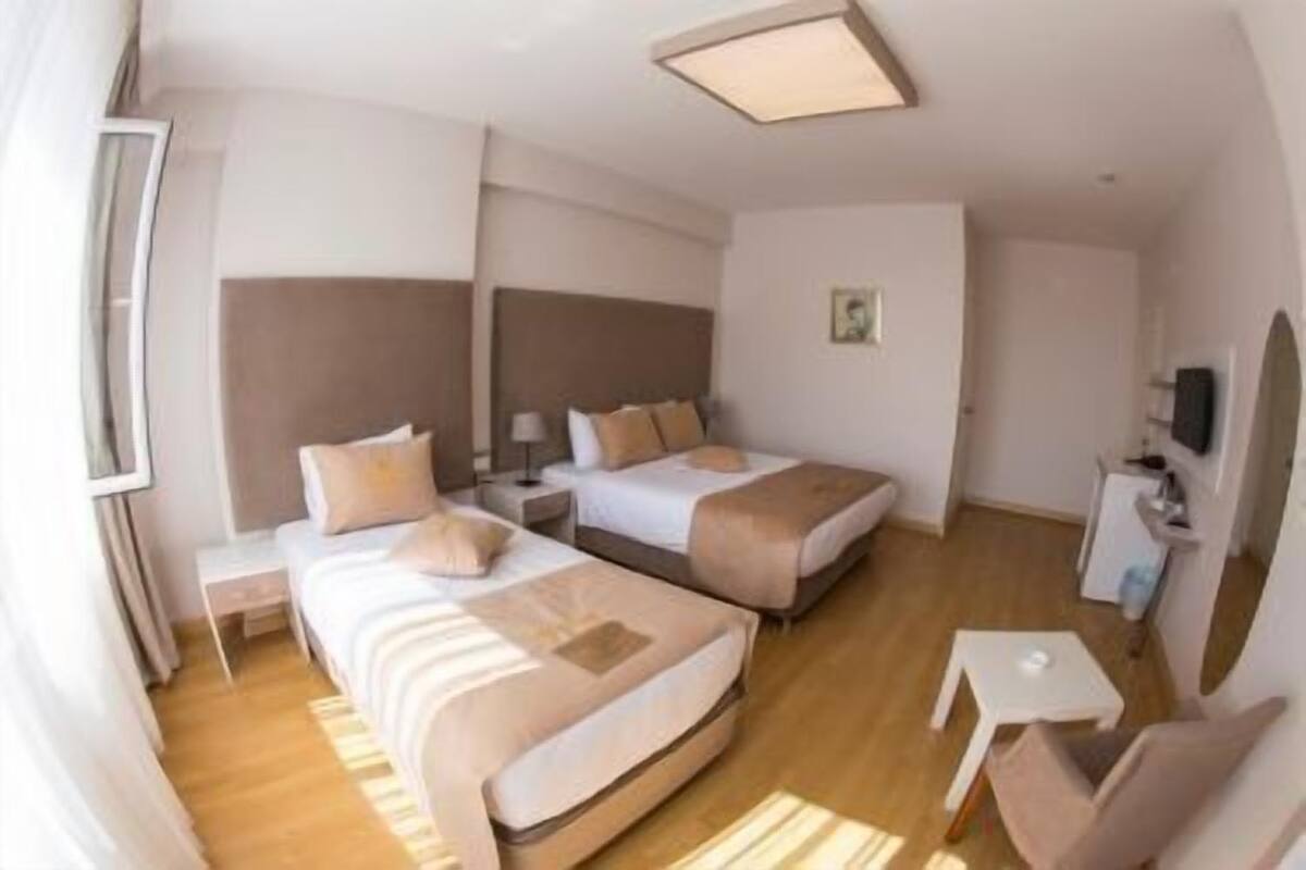 Ein Hotelzimmer mit zwei Betten, einem kleinen Schreibtisch, einem Stuhl und einem Fernseher.