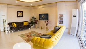 A modern hotel lobby with a black leather sofa, a yellow tufted sofa, a white round table, and a large window with a view. - Bilge Suite Hotel (Corum)
