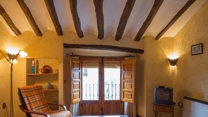 A cozy room with wooden beams, a plaid chair, a television, and a small table. - Molino de Morillas (Galera)