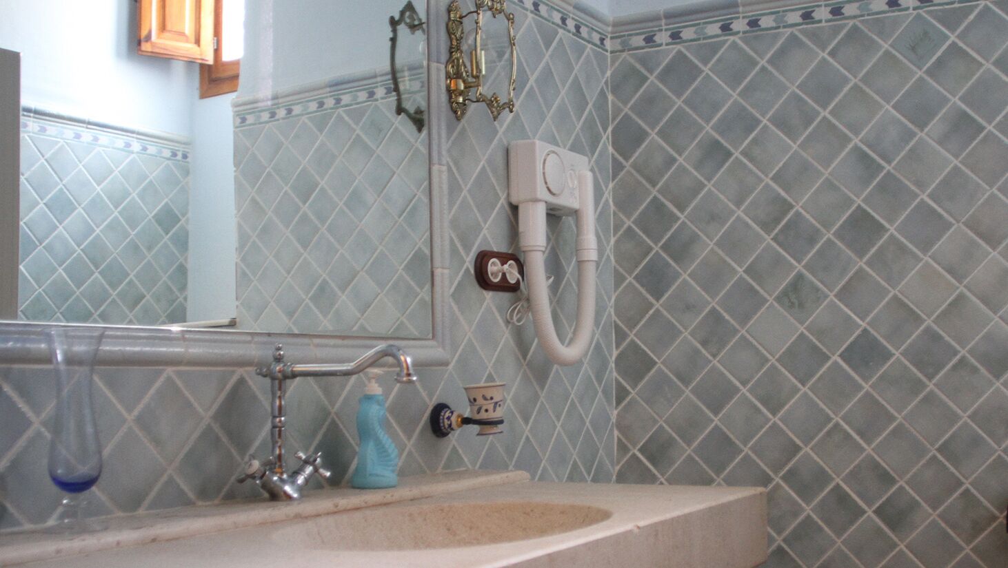 Baño con lavamanos, espejo y un inodoro de pared.