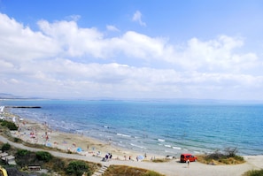 Une plage avec des gens, un véhicule rouge et un ciel dégagé.