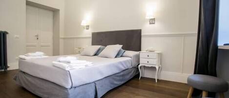 A neatly arranged bedroom with a bed, bedside tables, and a chair.