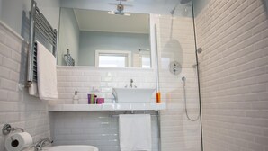 A modern bathroom with a glass shower enclosure, a white sink, and a bidet. - Relais della Torre (Rome)