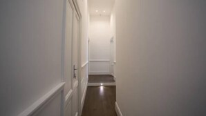 A narrow hallway with white walls and a wooden floor. - Relais della Torre (Rome)