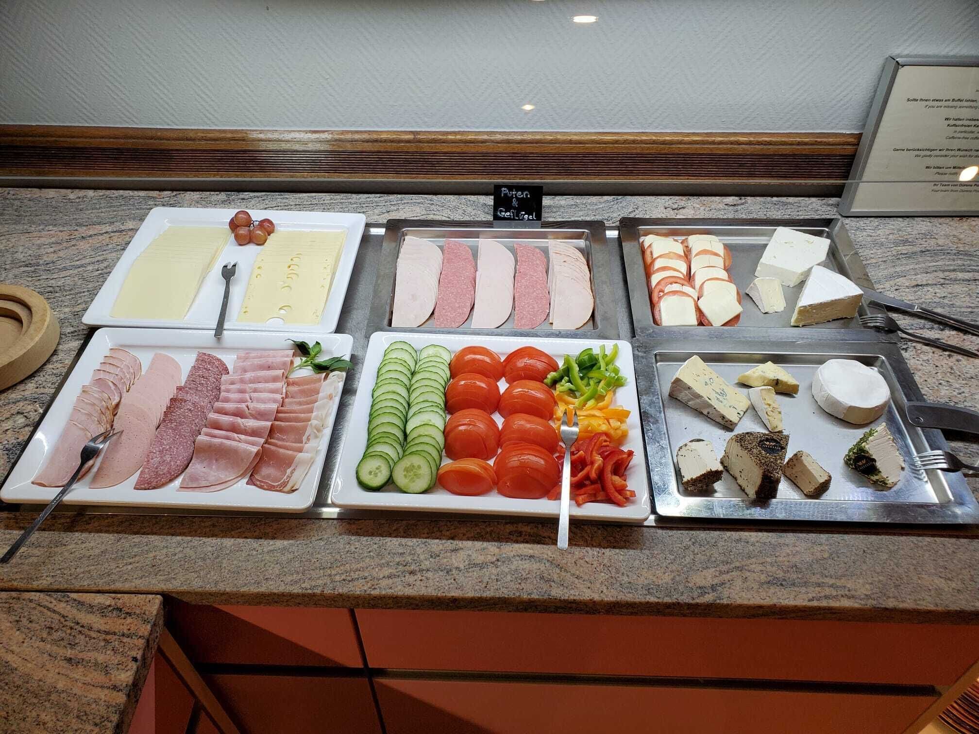 A buffet with various meats, cheeses, and vegetables.