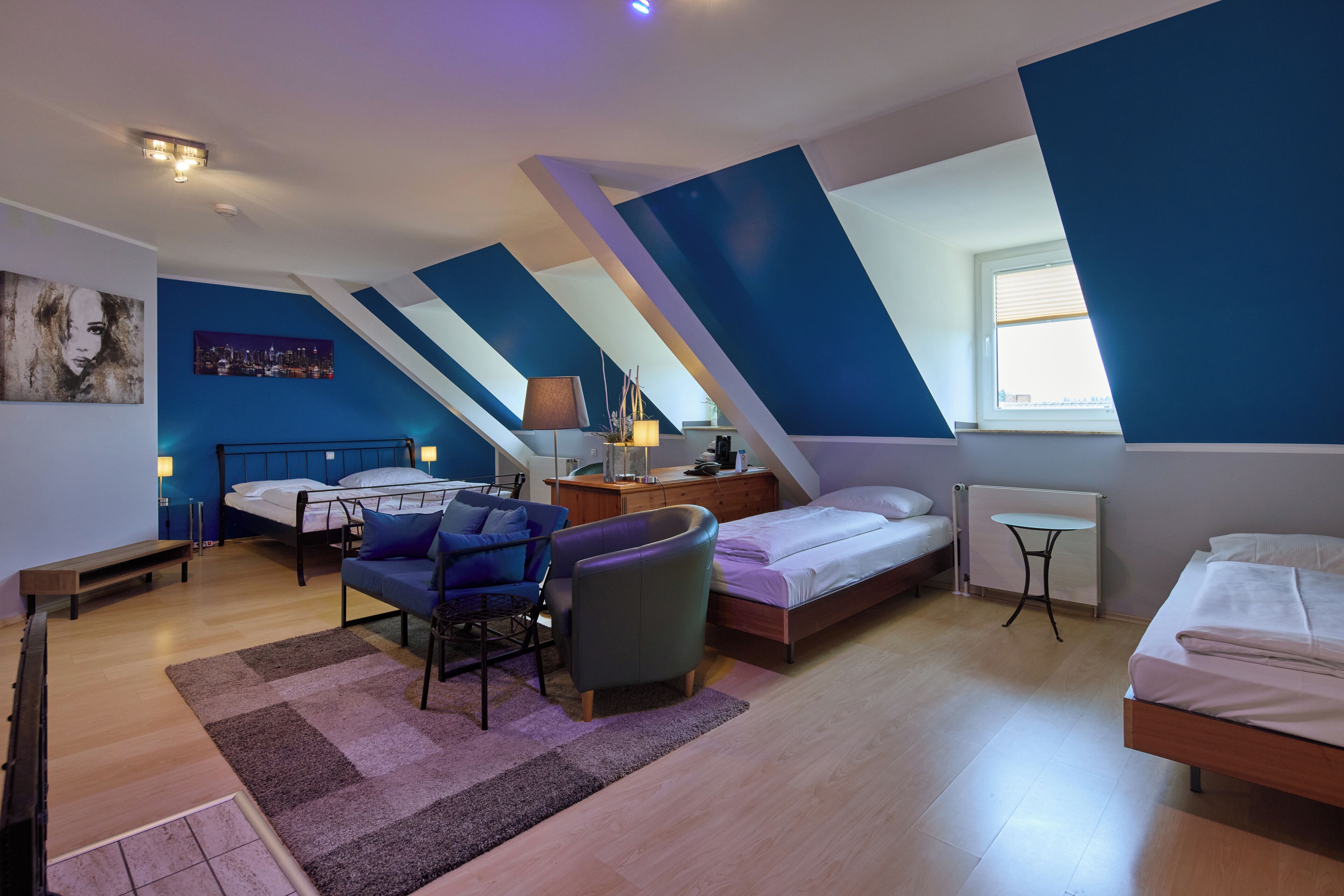 Ein modernes Schlafzimmer im Loft-Stil mit schrägem Dach, einem Bett, einem Schreibtisch und einem Sessel.