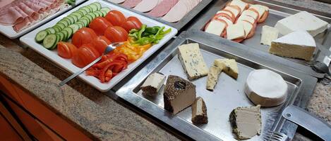 Un bufé con diversas opciones de comida, incluyendo carnes, quesos y vegetales.