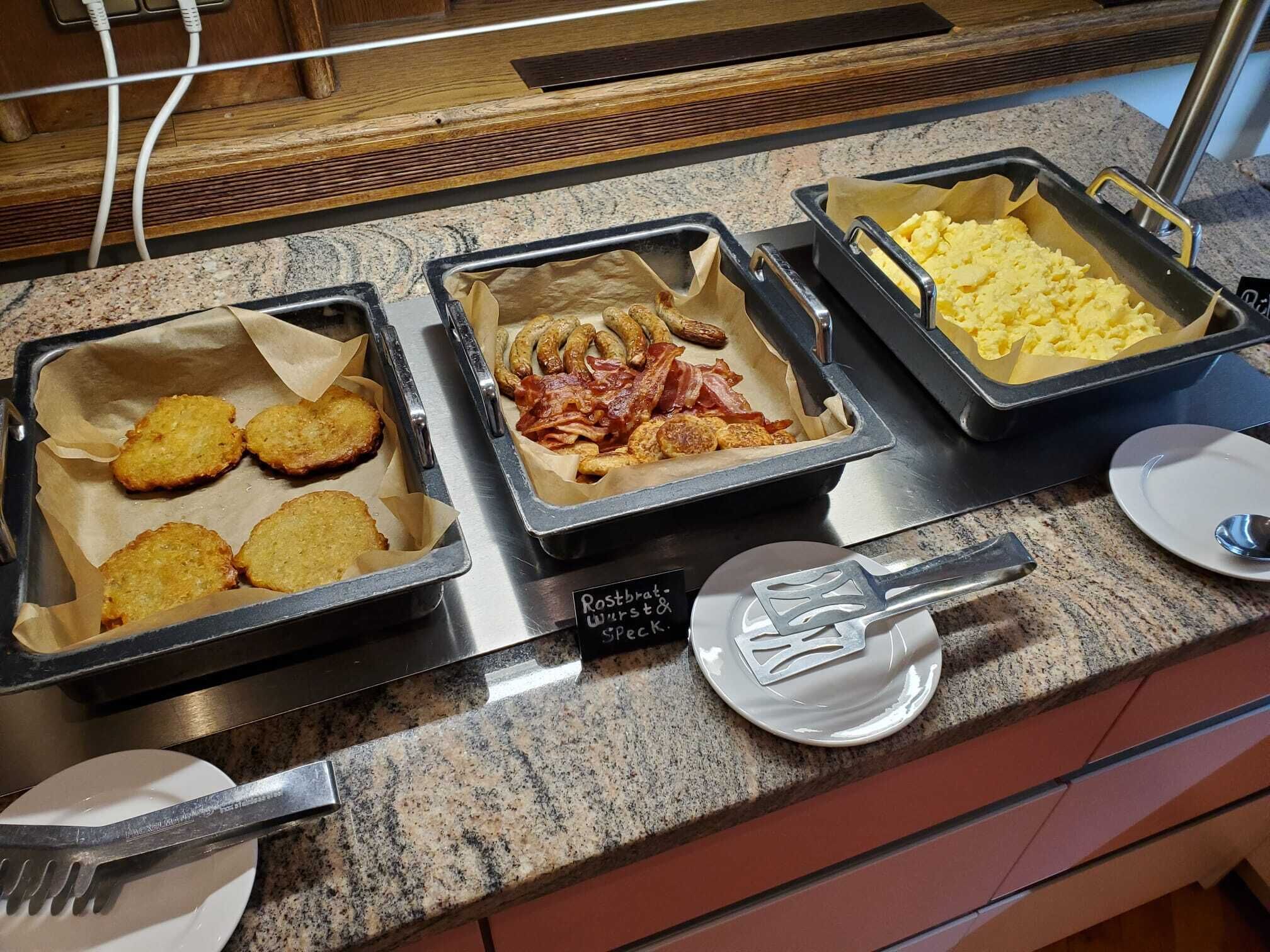 Ein Buffet mit Speisen, darunter panierten Gerichten, Speck und Rührei.