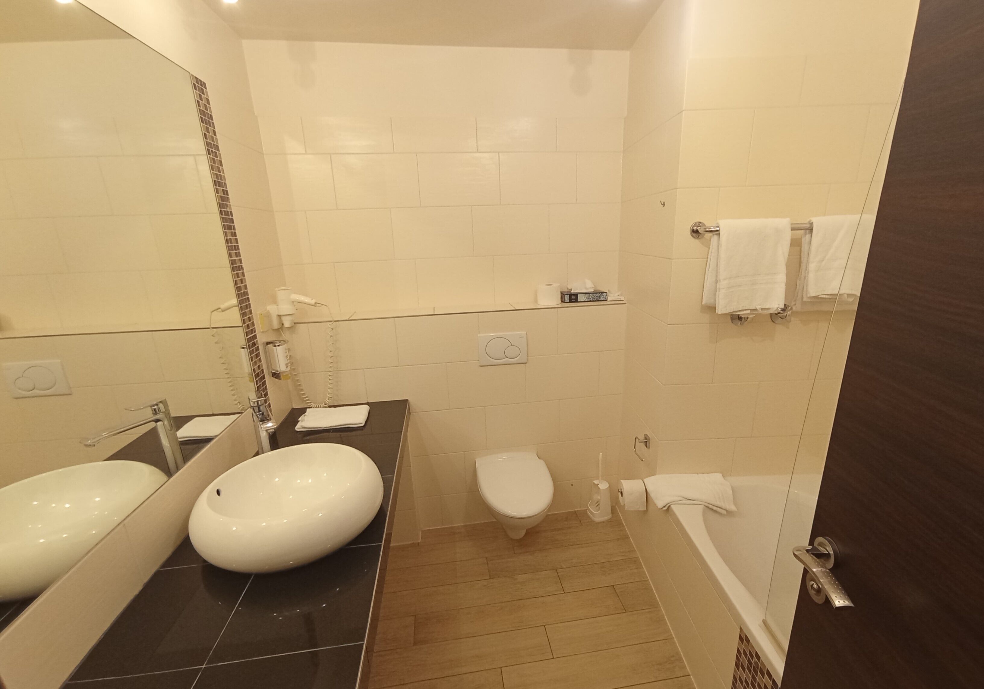 A modern bathroom with two sinks, a toilet, and a bathtub.