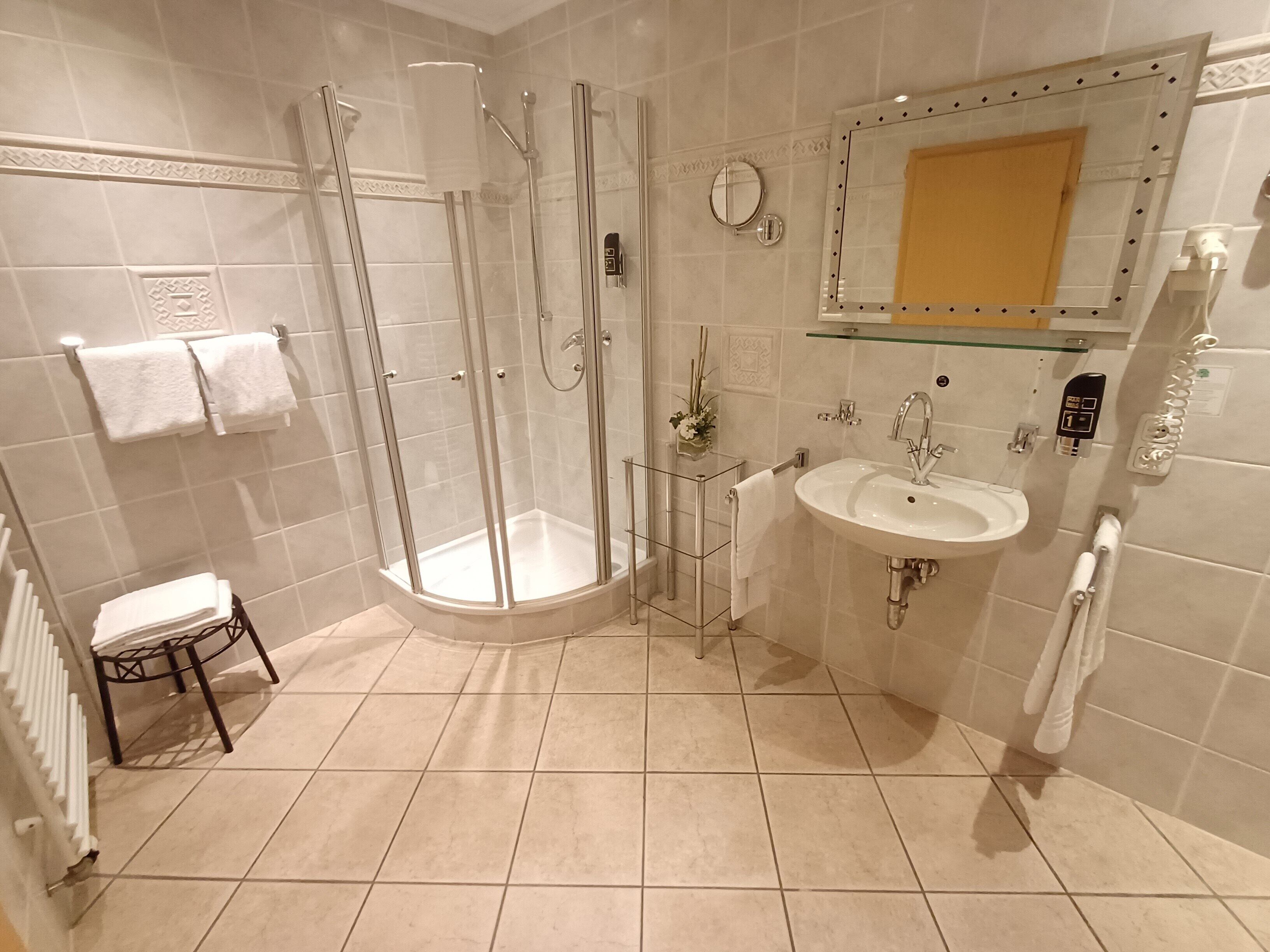 A modern bathroom with a glass-enclosed shower, a sink, and a mirror.