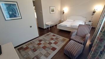 A bedroom with a bed, a bedside table, a chair, a rug, and two wall-mounted lamps.