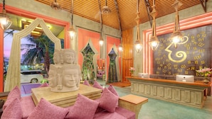 A reception area with a wooden reception desk, a statue, and a wall with decorative script. - Golden Temple Retreat (Siem Reap)