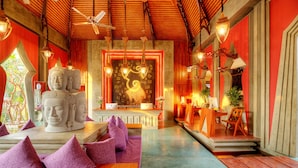 A room with a Buddha statue, a wooden reception desk, and a seating area with purple cushions. - Golden Temple Retreat (Siem Reap)