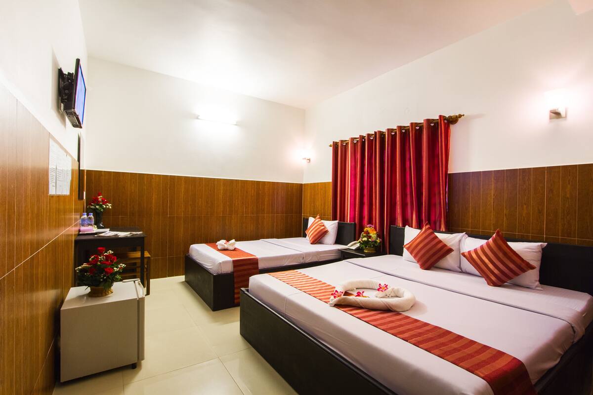 A hotel room with two beds, a desk, and a TV.
