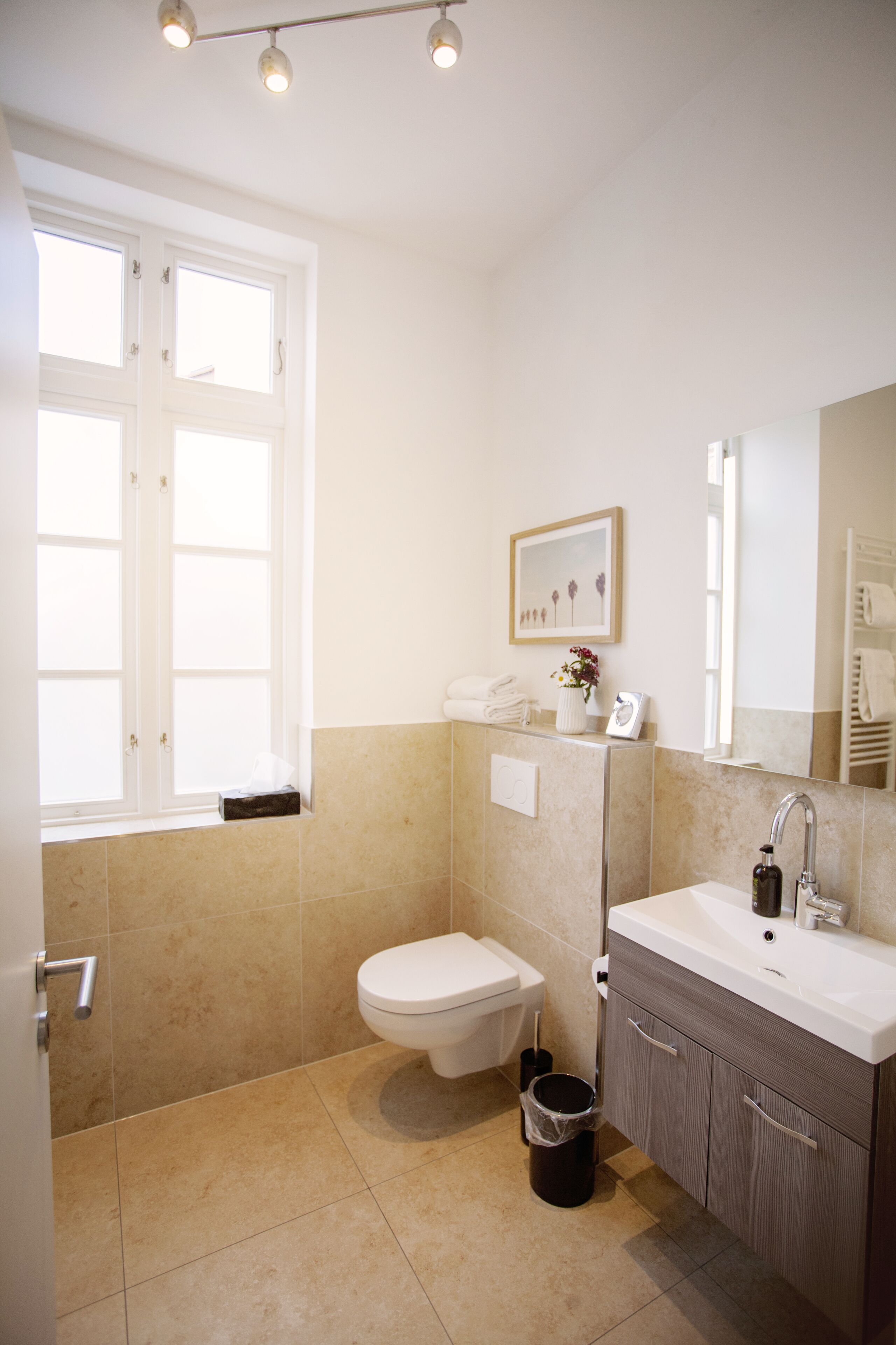 A bathroom with a toilet, sink, and window.