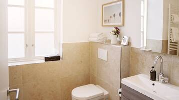 A bathroom with a toilet, sink, and window.