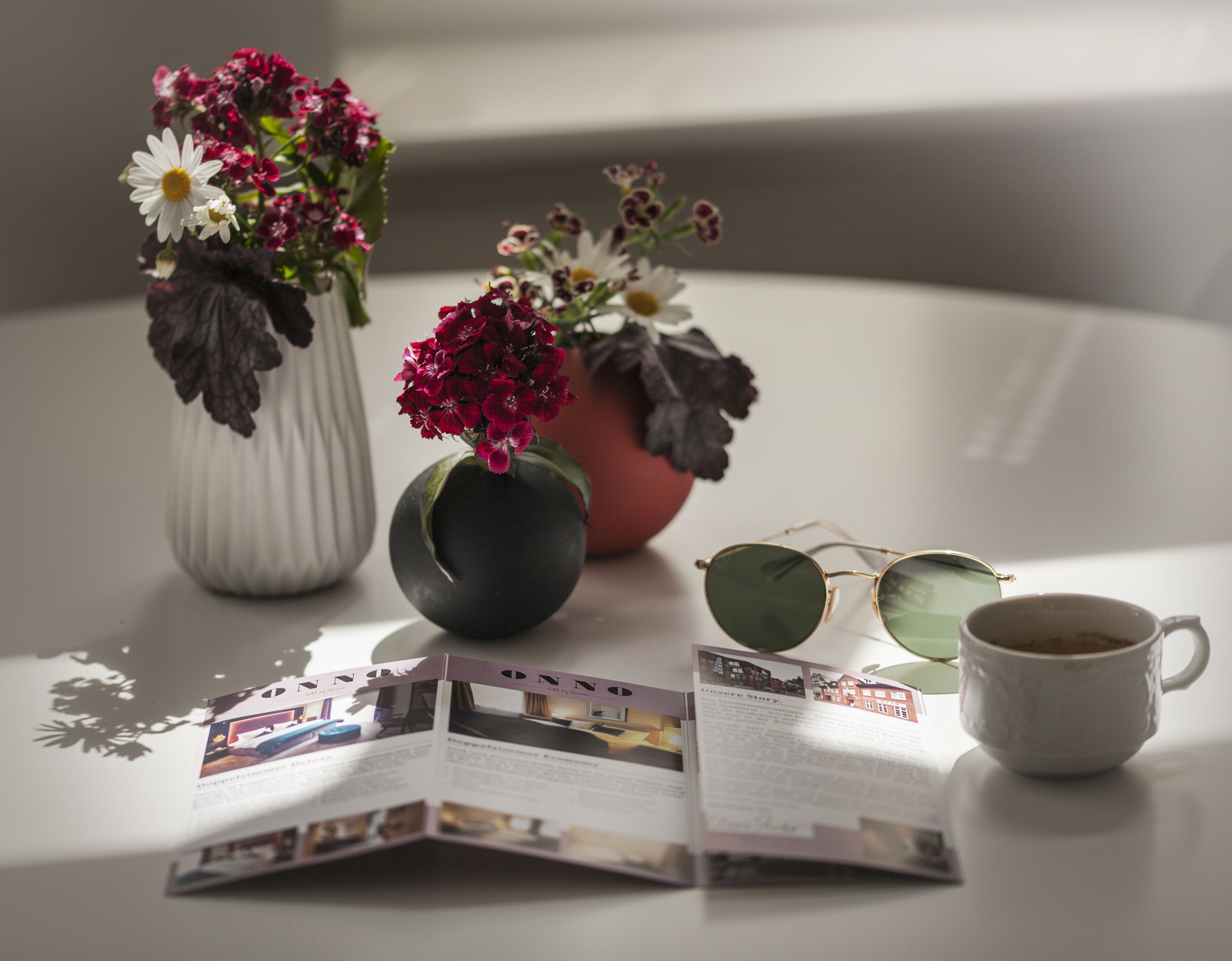 Une table avec deux vases de fleurs, une paire de lunettes et une tasse à café.
