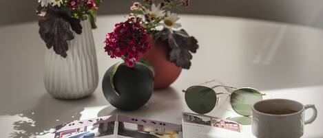 A table with two vases of flowers, a pair of glasses, and a coffee cup.