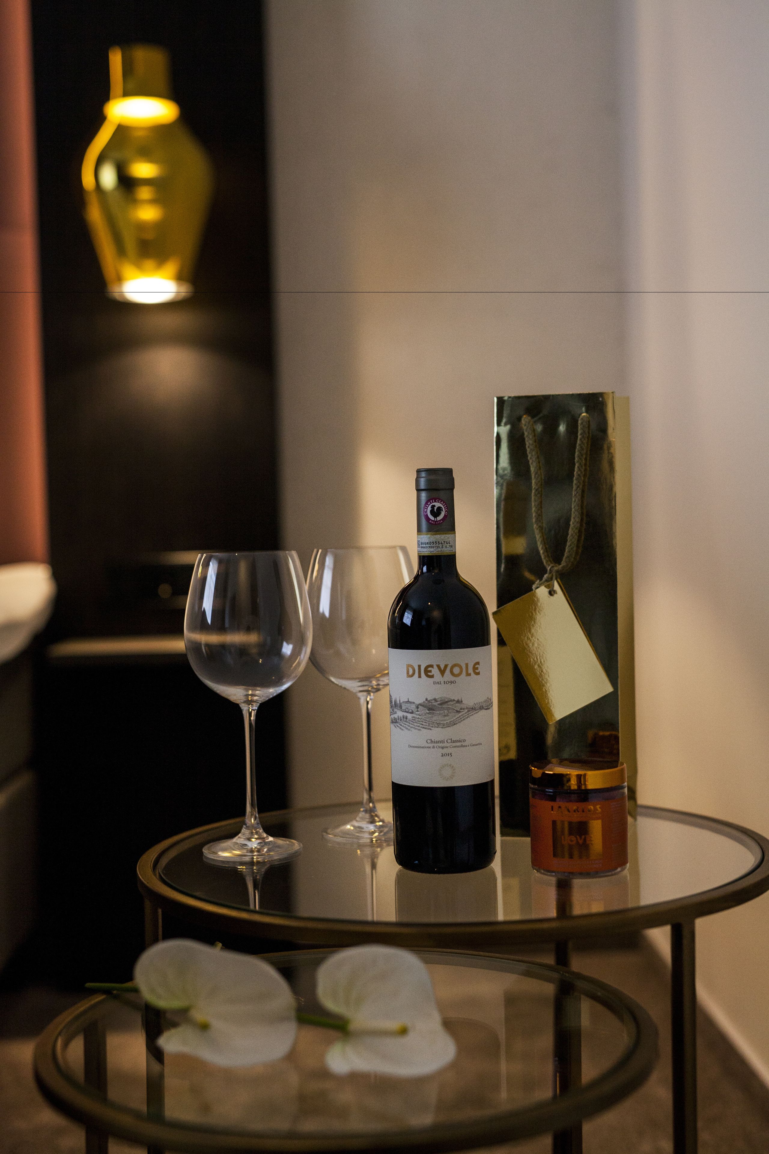 A bottle of D'ivoire wine, two empty wine glasses, and a small vase with flowers on a glass table.