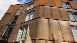 Un edificio moderno con diseño en esquina, ventanas amplias y cielo despejado.