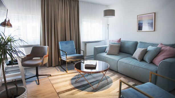 Una sala de estar moderna con un sofá, sillones, una mesa de centro y una lámpara de pie.