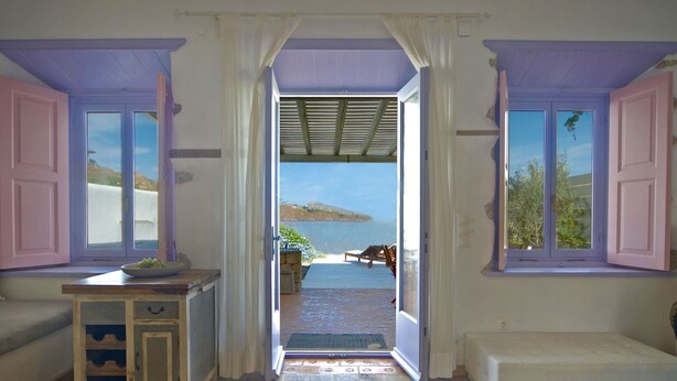 Una habitación con vista a la playa, una banca y una mesita con un frutero.