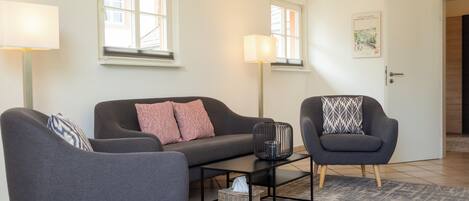 A modern living room with a grey sofa, two armchairs, a coffee table, and two floor lamps.