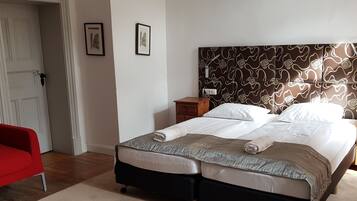 A bedroom with a bed, a nightstand, a red chair, and a door.