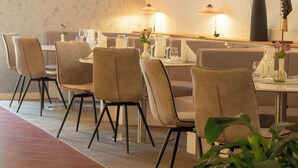Un restaurante con una decoración moderna, con mesas dispuestas con manteles blancos y sillas, y un jarrón con flores sobre la mesa.