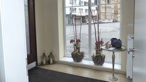 A hotel room entrance with a large window, a door, and a small table with a vase and a book. - Hotel am Ludwigsplatz (Giessen)