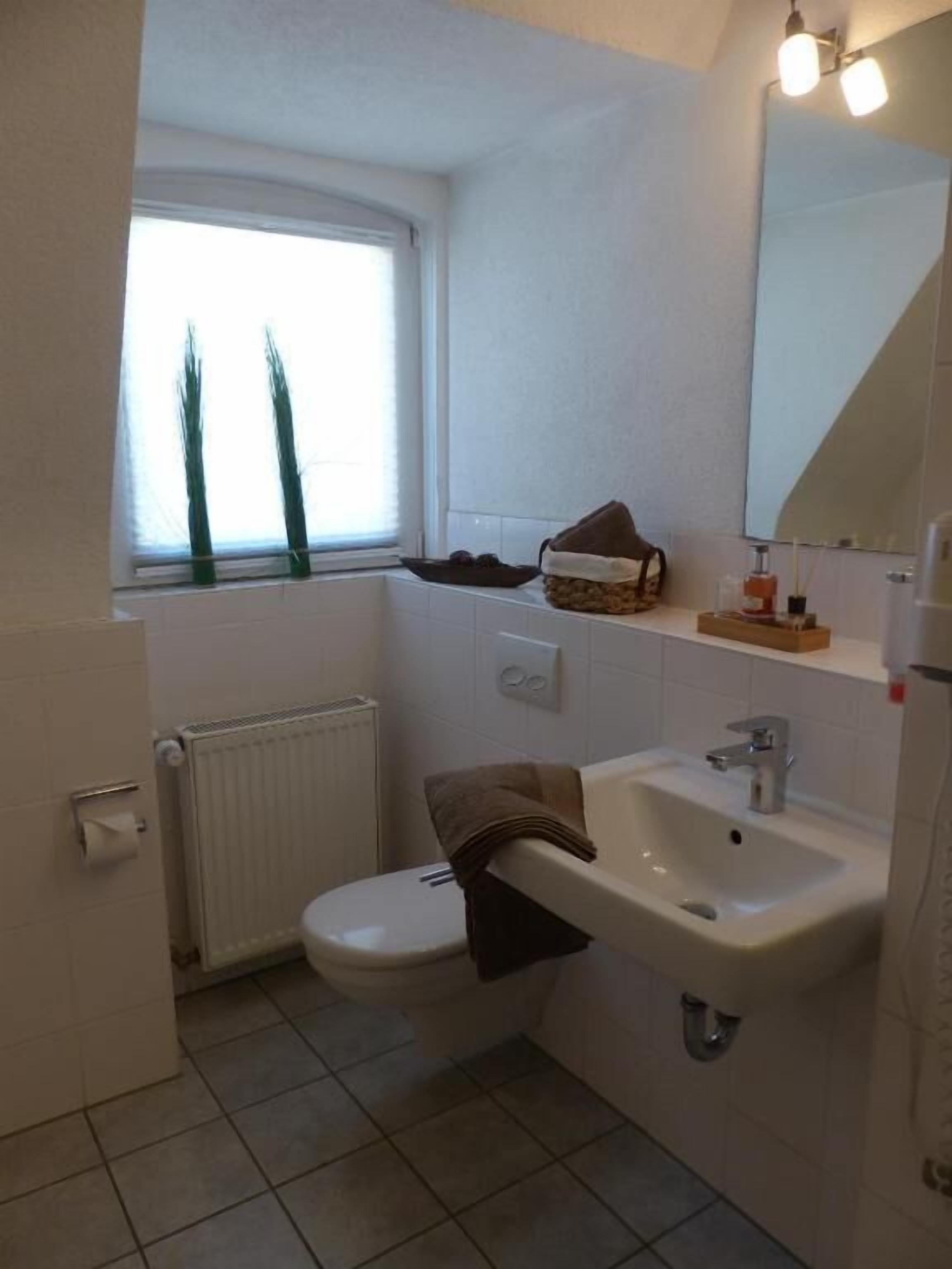 A small bathroom with a toilet, sink, and window.