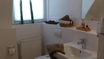 A small bathroom with a toilet, sink, and window.
