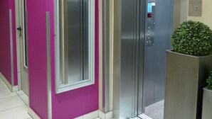 A hallway with a purple wall, a door, and an elevator. - Hotel am Ludwigsplatz (Giessen)