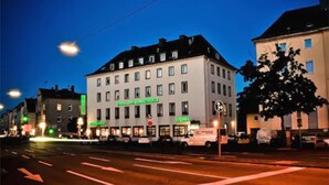 A hotel with multiple floors, a prominent sign, and a street view with traffic lights and vehicles. - Hotel am Ludwigsplatz (Giessen)