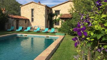 Una piscina al aire libre, sillones reclinables de piscina