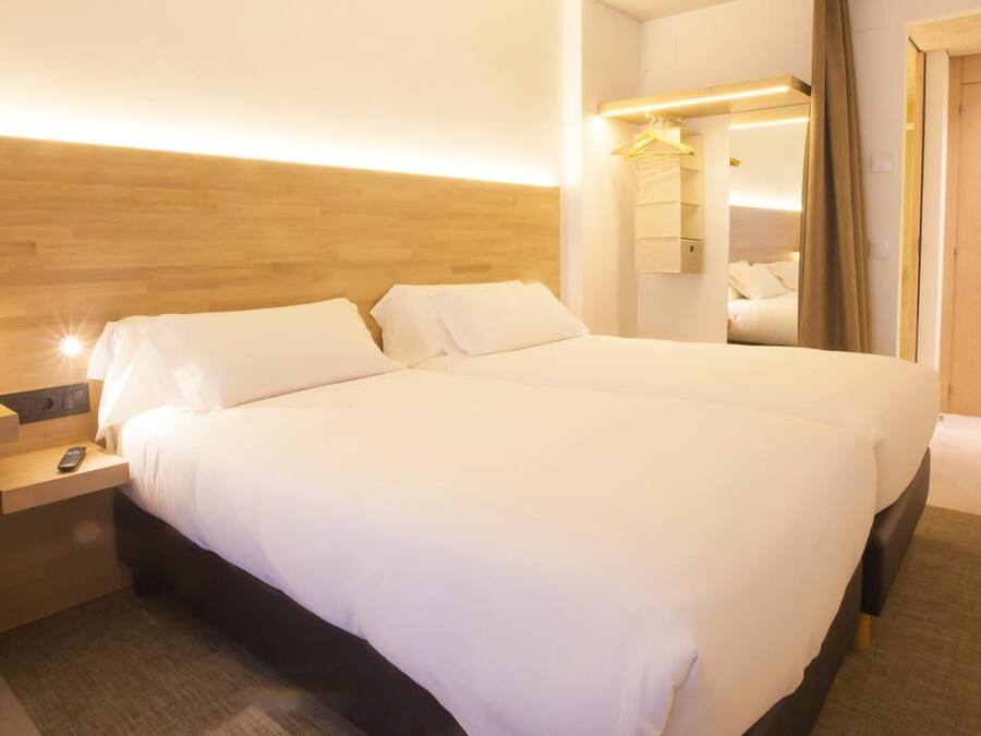 Una camera d'albergo con un letto grande, comodini, una scrivania e uno specchio.