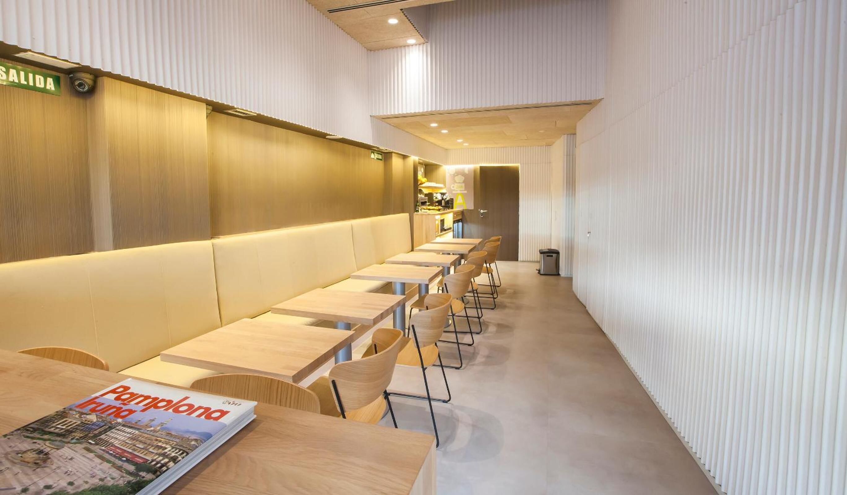 Un ristorante moderno con lunghi tavoli in legno e sedute imbottite.