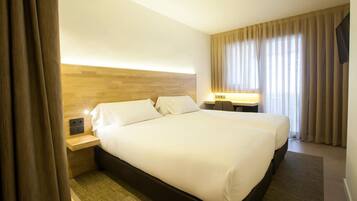 Habitación de hotel con una cama grande, dos mesitas de noche, un escritorio y una televisión.