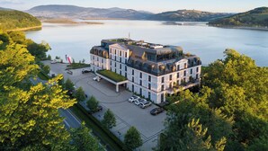 Un hotel moderno con fachada de vidrio, situado cerca de un lago y vistas a montañas.