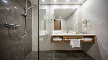Une salle de bain moderne dotée d’une douche à parois de verre, d’un meuble-lavabo en bois avec un porte-serviettes et d’un miroir au-dessus du lavabo.