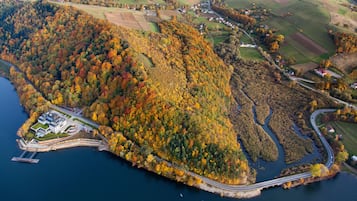 An aerial view of a coastal area with a bridge connecting an island to the mainland, surrounded by autumn-colored trees and fields.