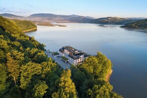 A large, modern hotel with a rooftop terrace, surrounded by dense forest and a large lake. - Heron Live Hotel (Grodek Nad Dunajcem)