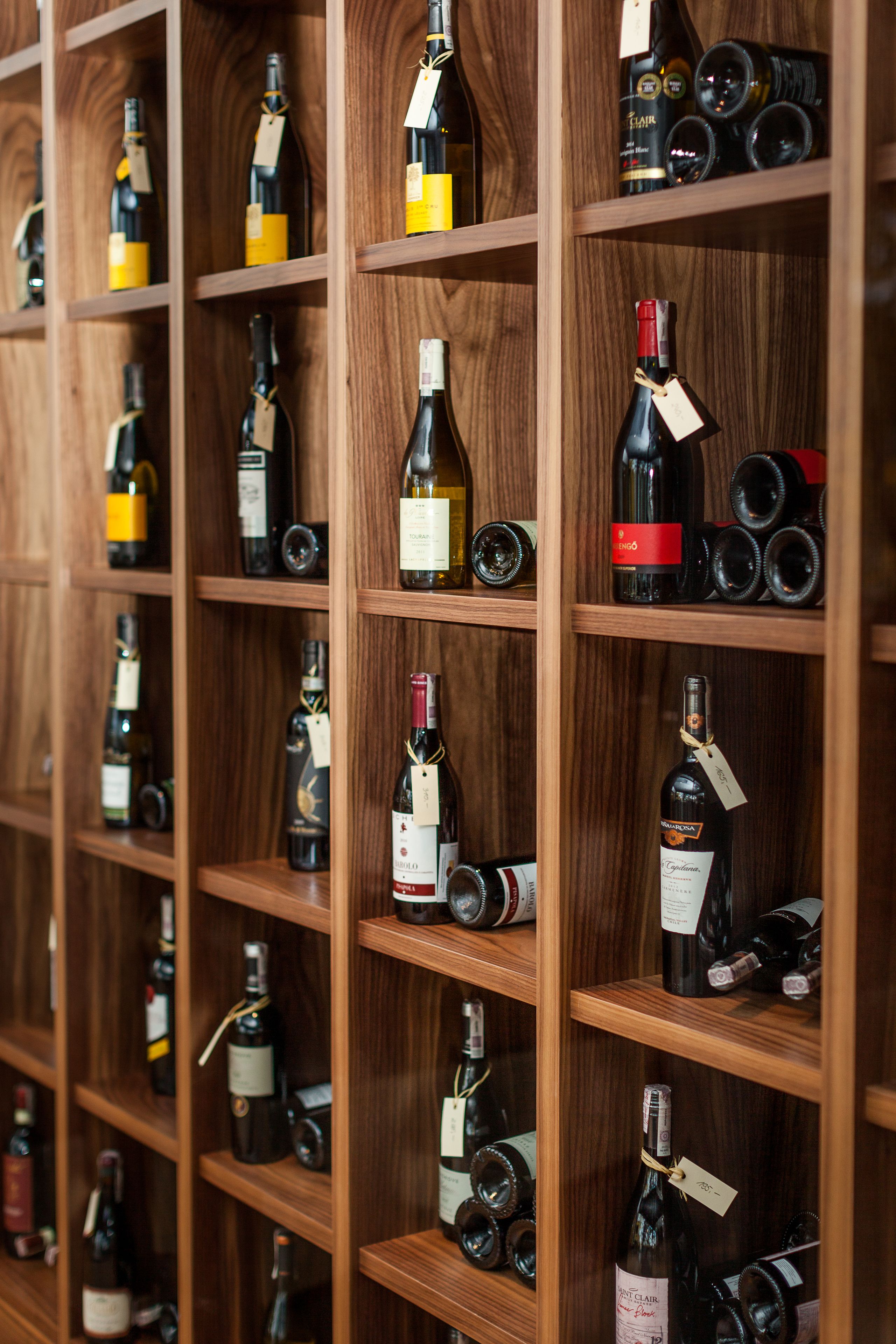 Un mur composé d’étagères en bois où sont alignées de nombreuses bouteilles de vin.